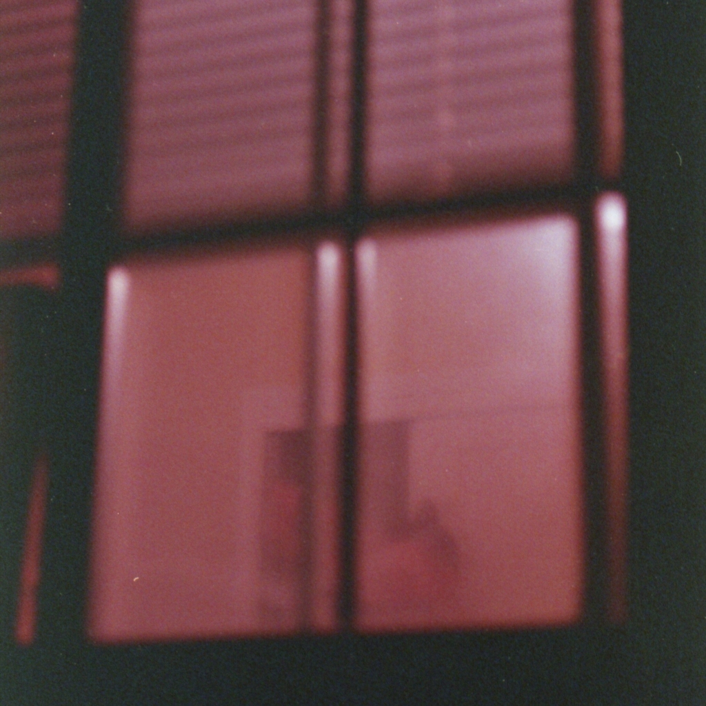 a deep red look inside a building from outside a window. album cover for maysayer single "exposing the dust"